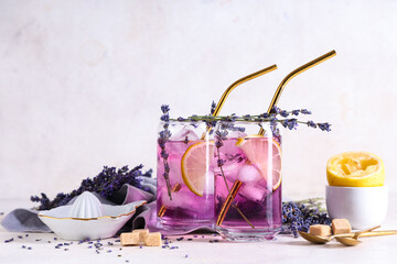 Glasses of fresh lavender lemonade with flowers and juicer on white background