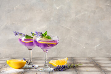 Glasses of fresh lavender lemonade with mint and flowers on grey tile table