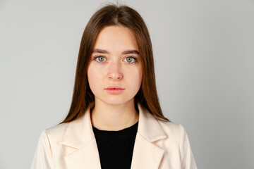 Young Woman in White Jacket and Black Pants on Gray Background.