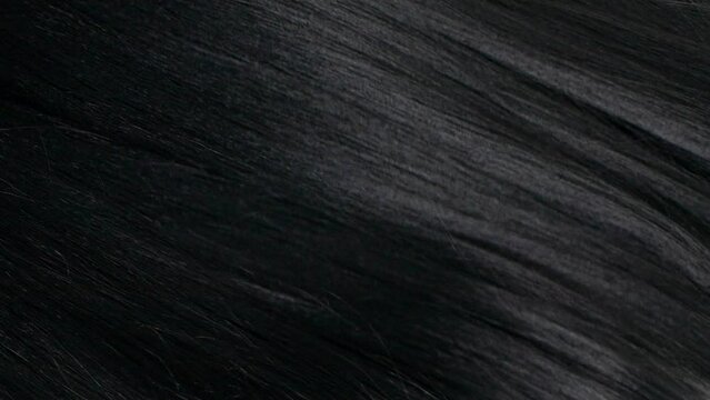Closeup human long hair texture in slow motion, black straight hair background
