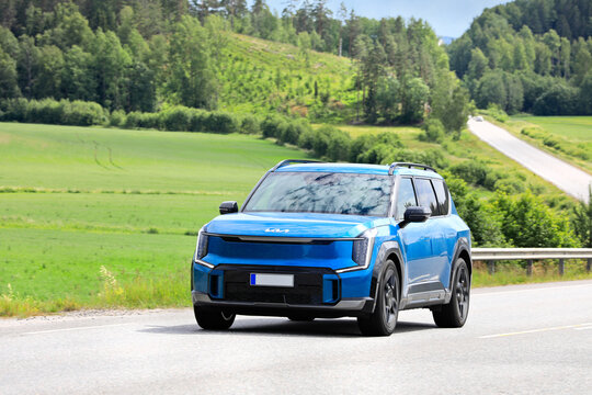 2024 blue Kia EV9 SUV car on road on a day of summer. 