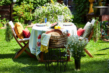 A bright, festive outdoor garden setting in a yellow and red palette with wildflowers, berries and watermelon