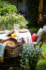 A bright, festive outdoor garden setting in a yellow and red palette with wildflowers, berries and watermelon