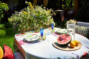 A bright, festive outdoor garden setting in a yellow and red palette with wildflowers, berries and watermelon