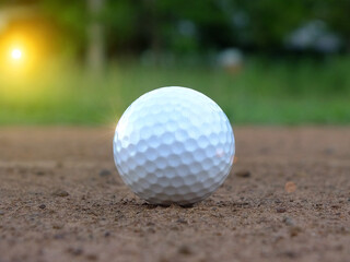 The white golf ball is outside the greens closely on the green background. And beautiful evening sky With the sun shining