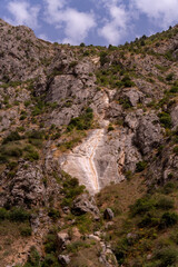 A mountain with a cliff face and a small path leading down it