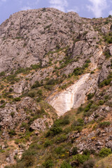 A mountain with a cliff and a waterfall