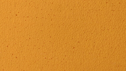 Close-up of a textured orange sponge with small holes. Ideal for cleaning, household, and kitchen backgrounds