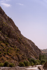 A mountain with a rocky cliff and a river running through it