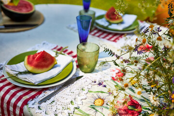 A bright, festive outdoor garden setting in a yellow and red palette with wildflowers, berries and watermelon