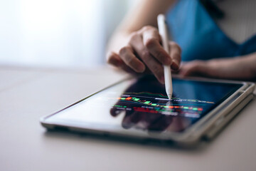 Close-up of a woman's hands using a digital tablet to watch the stock market