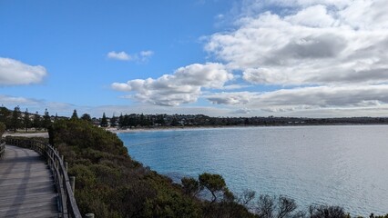 Fototapeta premium Middleton Beach Albany WA. Blue water from, Frenchman's Bay, A blue cloud scattered Sky, pine trees adorning the beach, yellow sand and native foliage. Tourism stock photo 