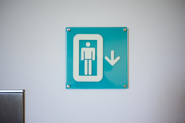 Sign depicting person in elevator with downward arrow. Signpost in office, shopping center,...