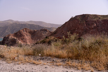 A barren landscape with a rocky hillside and a body of water in the distance