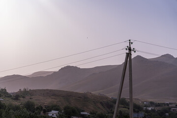 A tall power line pole is standing in the middle of a field