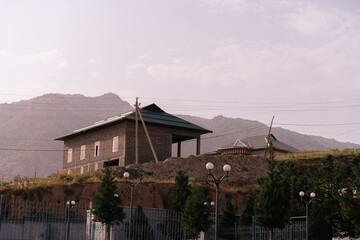 A small house sits on a hillside next to a fence