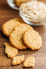 Tasty oatmeal cookies and rolled oat on wooden table.