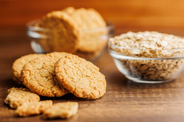 Tasty oatmeal cookies and rolled oat on wooden table.