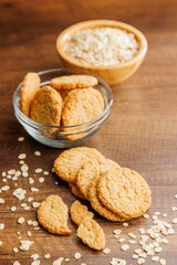 Tasty oatmeal cookies and rolled oat on wooden table.