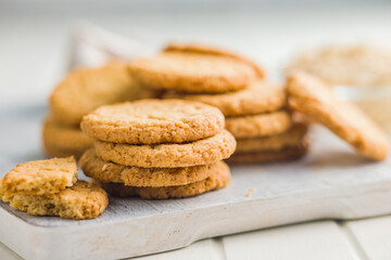 Tasty oatmeal cookies on cutting board on white table.