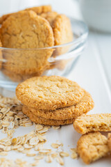 Tasty oatmeal cookies and rolled oat on white table.