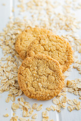 Tasty oatmeal cookies and rolled oat on white table.