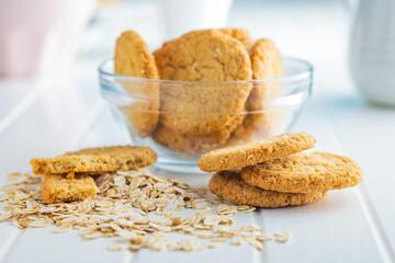 Tasty oatmeal cookies and rolled oat on white table.