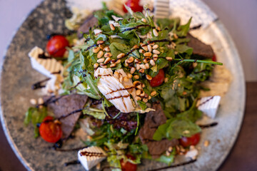 A plate of food with a salad on top and a piece of meat