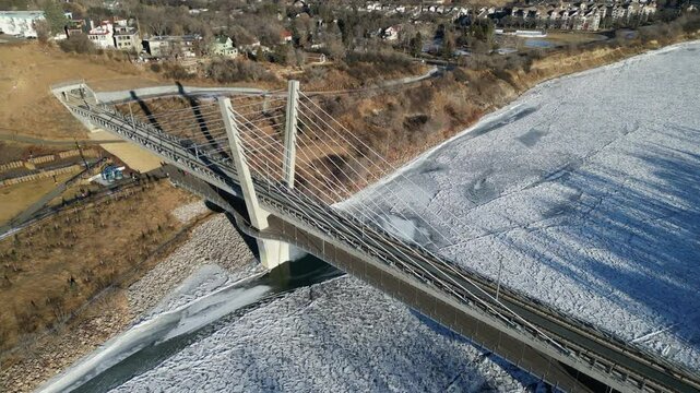 Aerial view of cable-stayed transit bridge on frozen river in Edmonton