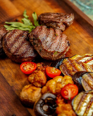 Elevated side view grilled meat cutlet with eggplant mushroom tomatoes and rosemary on a board. Food Photography