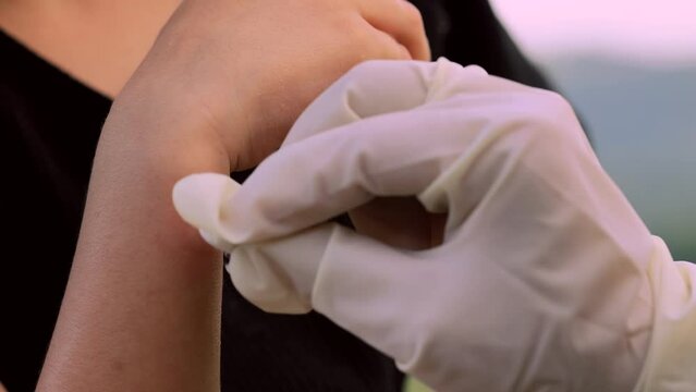 close-up photo of a mother applying spray to her child's hand after an insect, mosquito or bee bite in the summer in the yard