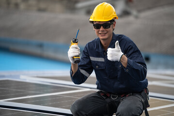 Engineer worker showing thumbs up while working on installed solar cell panel on the roof of the factory. Guarantee for quality control. Industrial renewable energy concept