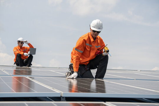 Engineer team checking solar cell or photovoltaic cell by electronic device installed on the roof of the factory. Technician worker repair or inspect the system. Industrial renewable energy concept - Powered by Adobe