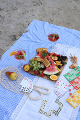 Fototapeta premium summer picnic on the seashore. board games on a picnic blanket. dominoes, lotto and cards. fruits and berries for a snack