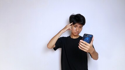 Fototapeta premium Young Asian man wearing black shirt looking and thinking something smartphone