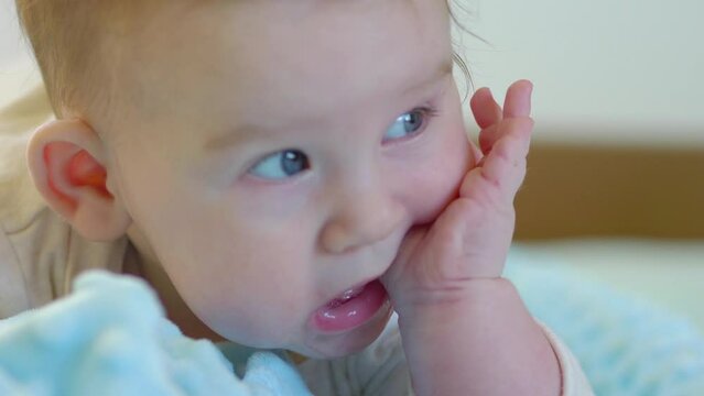 Teething baby puts his hands in his mouth in 4k slow motion 60fps