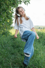 A child  with headphones listening to music and dancing in the park.