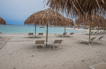 Serene Beach with Straw Umbrella and Lounge Chairs, ideal for relaxation and recreation