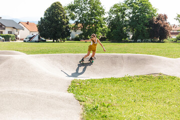 Happy and smiling young woman practicing skateboarding at a skate park. Girl wearing yellow...