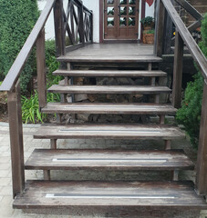 Wooden steps lead to the porch of the house. Steps with old handrails