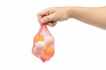 A male hand holding a net bag of yellow and white ping pong balls isolated on white background