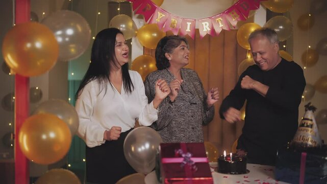 Indian Asian old aged cute male female man lady wife adult friends do funny dance music night party decor house happy elder gen x retired mom dad family group have fun joy enjoy joyful spend time home