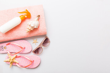 Summer holiday concept. Top view of beach towel, flip flop and sunscreen cream on table Top view...