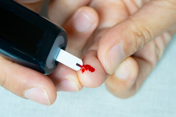 Woman's hands checking diabetes and hyperglycemia with digital blood sugar meter. Healthcare and...