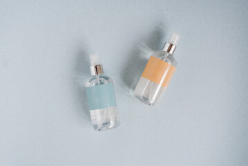 Two bottles of serum of perfume are on a blue background. One bottle is blue and the other is yellow