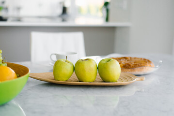 Green apples on a plate on a marble table in the kitchen. Healthy and wholesome food