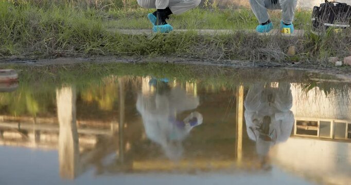 Crime, scene and investigation with forensic sample for evidence, marking or test on outdoor case by pond. Reflection of team investigators tracing leads, foot prints or DNA for CSI research by lake