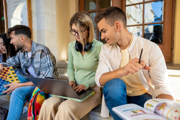 Students studying together while sitting on stairs in university campus