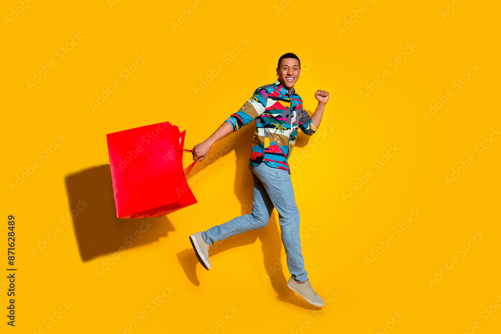 Poster Full length photo of nice young male running shopping bags dressed stylish colorful garment isolated on yellow color background