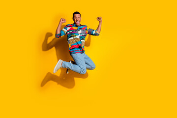 Full size photo of handsome young guy jump winning wear trendy colorful outfit isolated on yellow color background